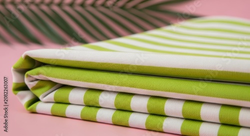 A stack of folded green and white striped fabric on pink surface green fabric white stripes folded t