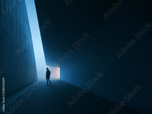 Person Standing in Modern Architectural Passage with Light