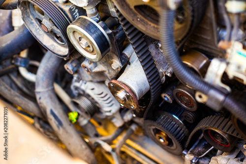 An extreme close-up of a car engine block with a black toothed timing belt and metal pulleys. automotive repair parts, vehicle motor.
