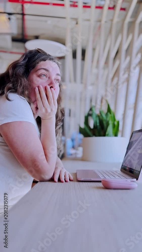 Tired freelancer woman yawning while working on laptop
