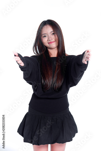 Portrait of a friendly young Asian woman in casual black clothing reaching out with open arms