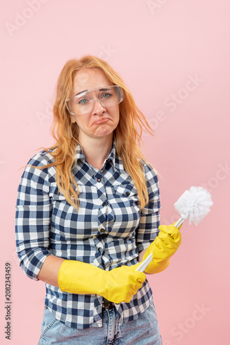 Obraz na plátne Woman wearing protective eyewear and yellow gloves holding a toilet brush, showi