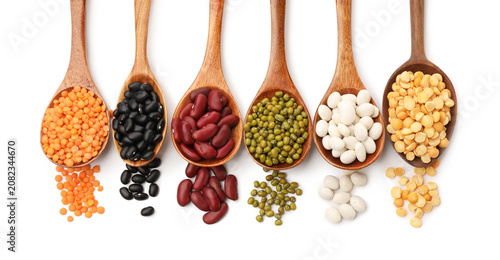 Obraz na płótnie Different types of legumes in wooden spoons isolated on white, top view