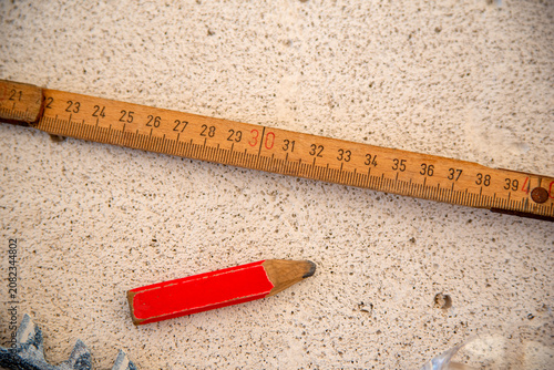 Foto Carpenter's red pencil beside a vintage wooden folding rule on a textured gray w
