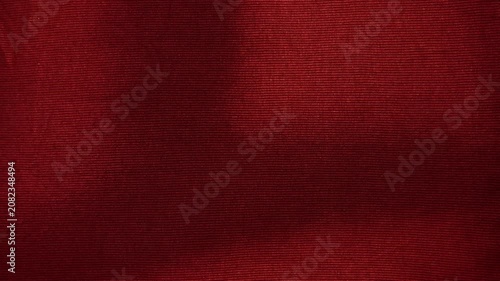 crimson red ribbed knit fabric texture moving gently under soft dramatic studio lighting creating subtle elegant shadows