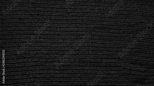 black knitted fabric texture reveals detailed woven wool rows in an elegant minimalist macro view