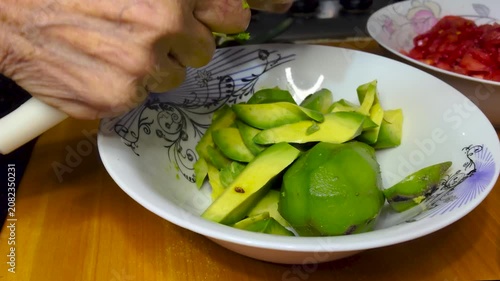 Close Up of Hands Slicing Fresh Ripe Avocado with Kitchen Knife into White Bowl During Home Kitchen Food and Meal Preparation for Healthy Homemade Recipes