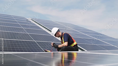Technician installing solar panels on factory roof for green energy. A skilled technician in safety gear is working on a solar panel installation on rooftop. clean energy renewable power technology.