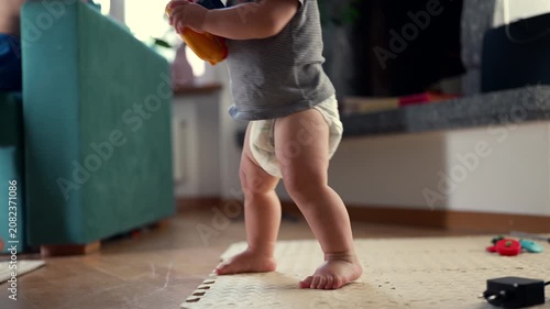 Toddler standing up while holding toy, highlighting gross motor development, early independence and childhood growth at home