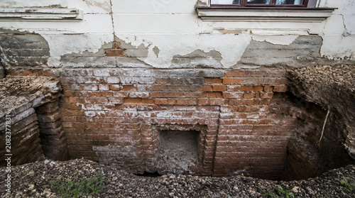 Excavation revealing old brick foundation wall under historical building