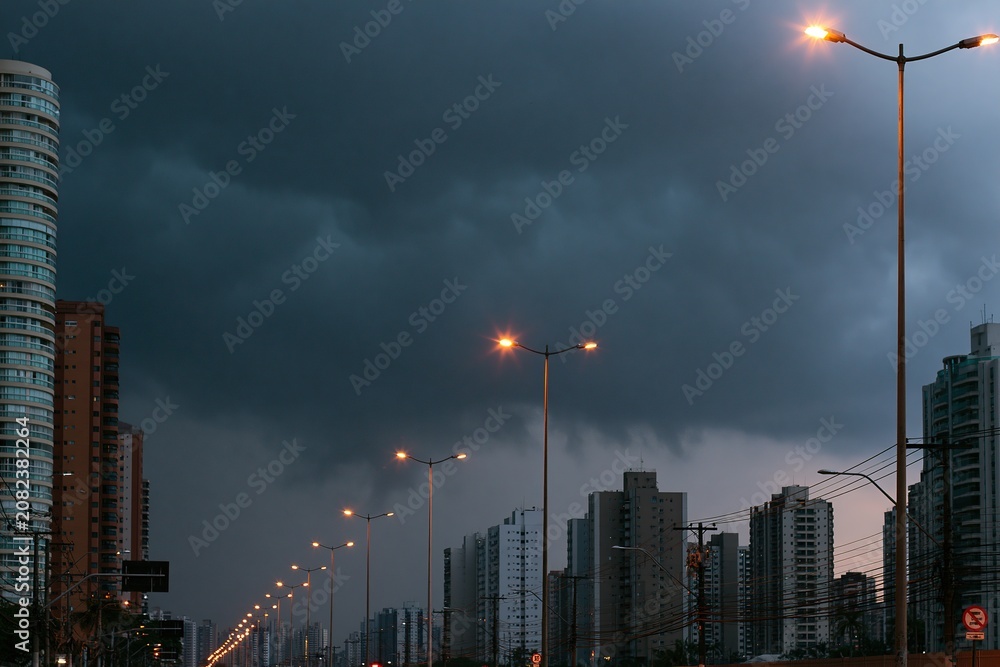 Obraz premium Stormy Sky Over Urban Landscape, Streetlights Illuminated