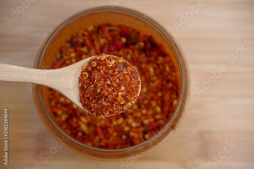 Close up of red chili powder in a wooden spoon over a bowl