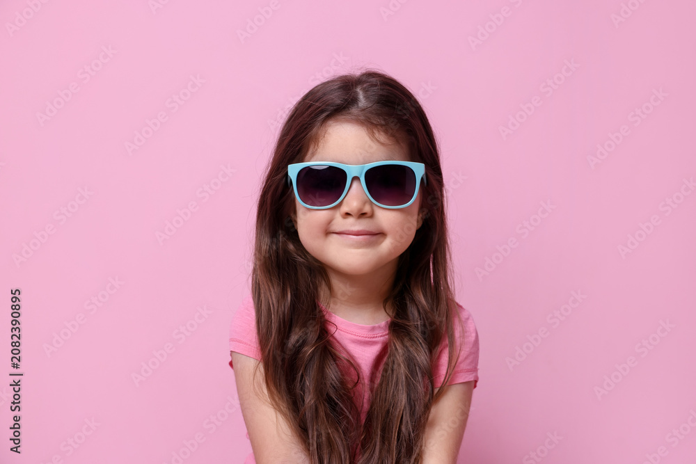 Fototapeta premium Cute little girl in sunglasses on pink background