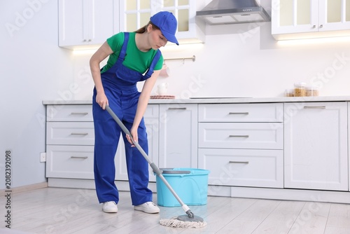 Tablou pe pânză Teenage worker mopping floor in kitchen. Part-time job
