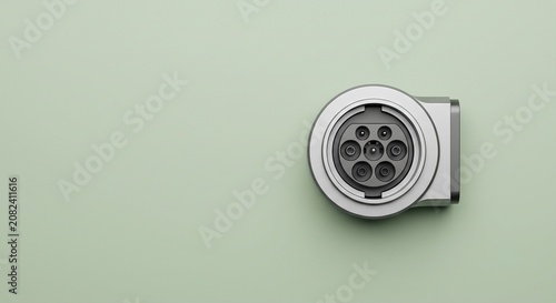 Minimalist EV charging plug component on sage green background