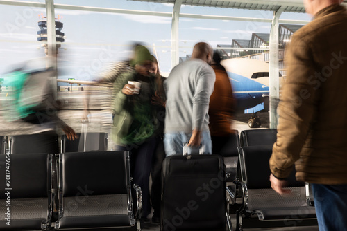 Obraz na plátně Pulling luggage, fast motion blur and hectic travelers in busy airport terminal, rushing, chaotic traffic flow