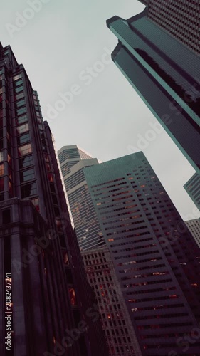 Tall buildings stand close together with glass windows reflecting light. This scene shows the city skyline during late afternoon. The sky appears cloudy above.
