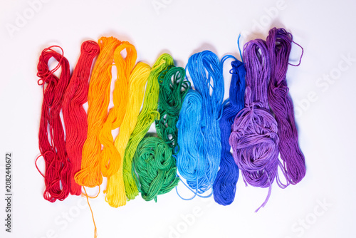 A rainbow of embroidery floss arranged casually on a white background.