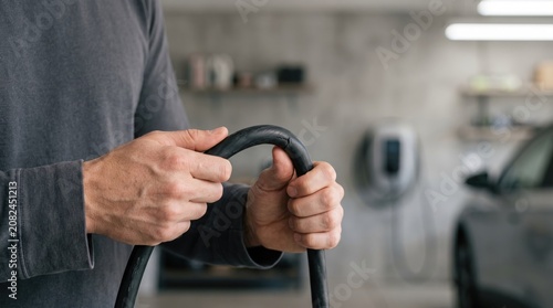 Person grips black vacuum hose in garage