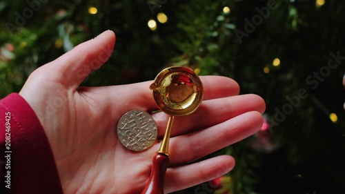 Fortune Telling for Good Luck.A hand holding a spoon with a tin coin ready for casting set against the backdrop of a Christmas tree. 4k footage