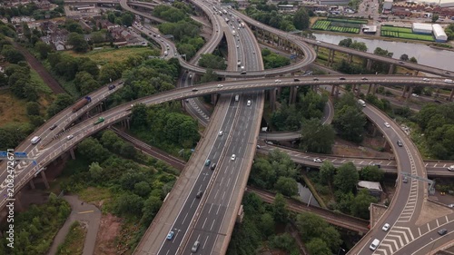 Low-altitude drone flight through the famous Spaghetti Junction motorway interchange in Birmingham, England. The aerial footage passes above multiple elevated M6 carriageways, curved flyovers
