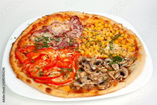 Whole baked four seasons pizza with mushrooms ham sweet corn and red bell pepper toppings on a white plate. Italian fast food, delicious cheesy dish, savory dinner meal pastry. Dining.