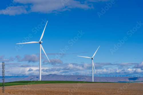 Wind turbines with green grass field, blue sky with clouds