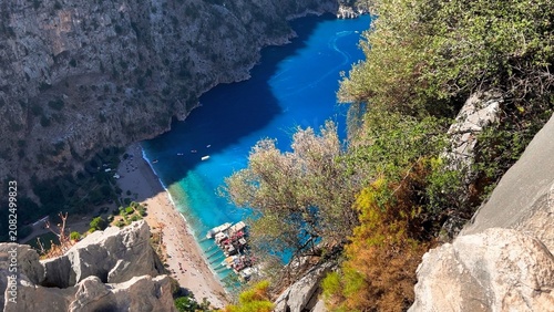 Butterfly Valley beach and turquoise cove seen through rocky cliffs and olive trees from a dramatic high vantage point, Fethiye, Turkey