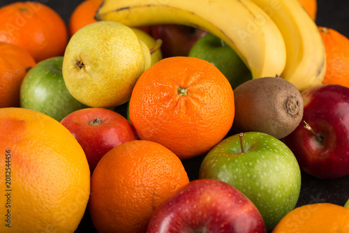 Tableau sur toile mix fruits colorful fruits ripe mellow fresh oranges and apples on dark desk