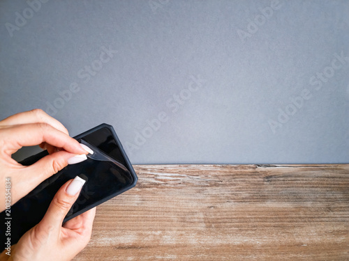 Obraz na plátně Woman hands applying a privacy screen protector on a smartphone with copy space