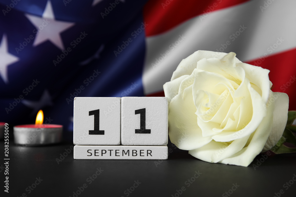 Obraz premium Calendar with rose flower and burning candle on black table against USA flag. National Day of Prayer and Remembrance for the Victims of the Terrorist Attacks