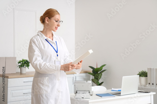 Happy female doctor with badge and folder in clinic