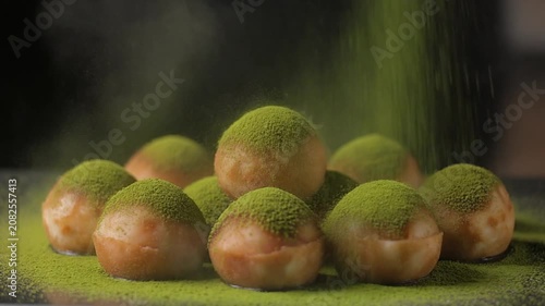 Matcha powder dusting over delicious round snacks in slow motion