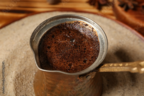 Pot with coffee in sand on ...