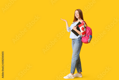 Female student with backpack and flag of Canada pointing at something on yell...