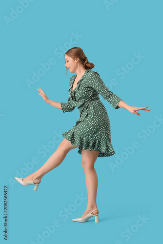 Beautiful young happy woman dancing on blue background