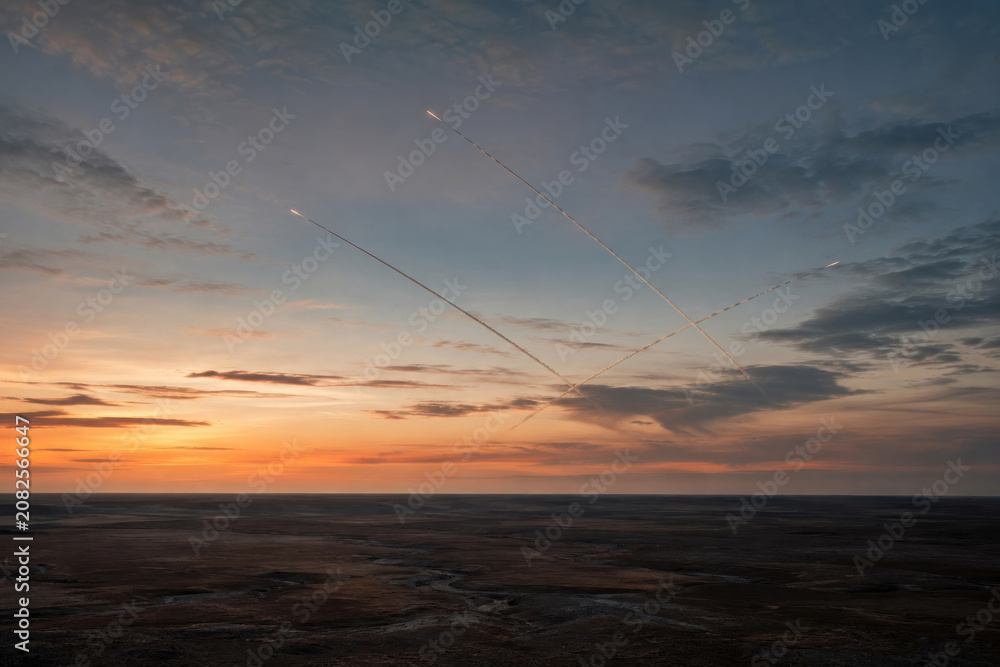 Fototapeta premium Multiple Missiles Crossing Twilight Sky Over Barren Landscape