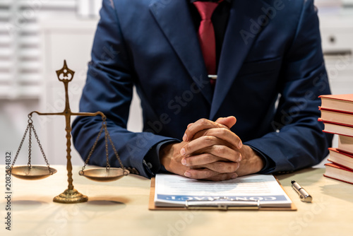 Photography Lawyer in suit sitting at desk with scales of justice, books, and clipboard, sho