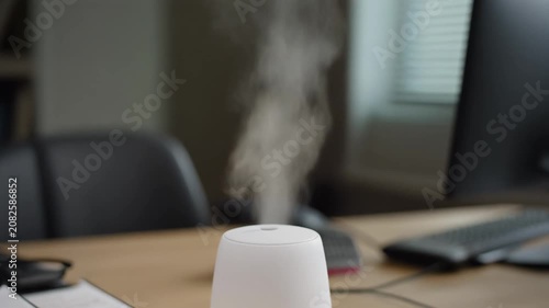White humidifier with steam on office desk