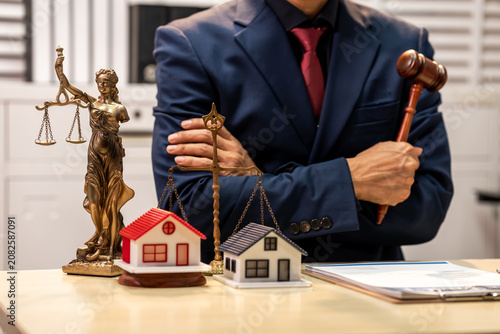 Businessman with gavel and justice statue beside model houses, showing real estate law, property dispute and legal advice concept.