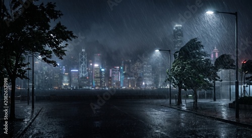 Naklejka 台風が通過する夜の都市イメージ：雨に煙る高層ビルのシルエットと冷たく光る横殴りの大雨