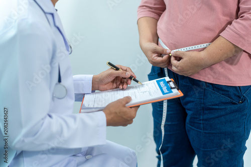Canvastavla Close-up of a healthcare worker measuring an overweight woman's waist with tape, showing weight control, obesity risk, body size check, and healthy lifestyle support