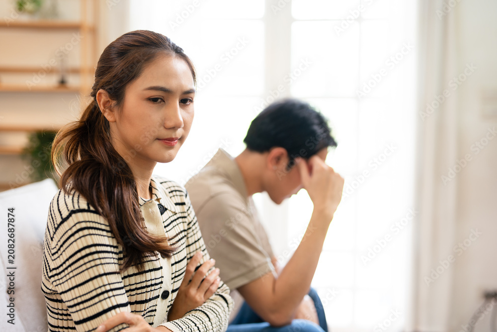 Fototapeta premium Relationship problems family crisis asian couple divorce marriage sad worried man husband thinking solution contemplating offended woman wife sitting in living room.