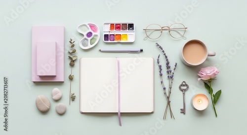 Flat lay of creative workspace with open notebook and art supplies.