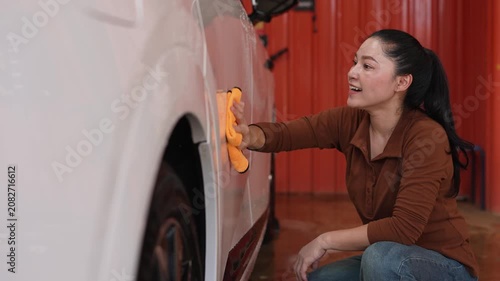 woman washing car with microfiber cloth in a self-service car wash station