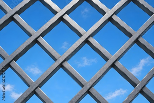 Metal lattice grid texture against a bright blue sky.