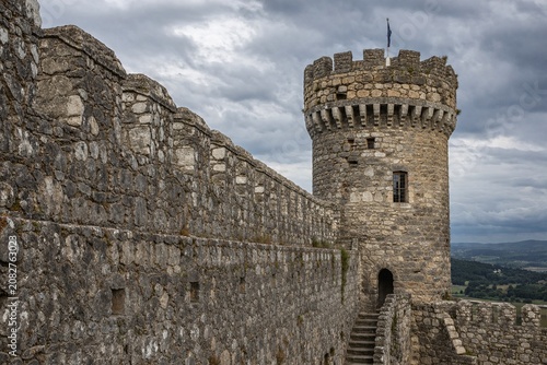 фотографія Weathered stone wall and watchtower of medieval castle under cloudy sky