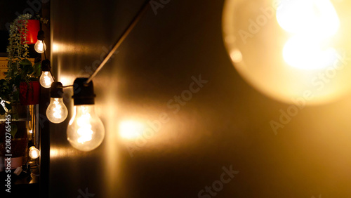 Schilderij op canvas String of a dozen warm glowing light bulbs creating a cozy, inviting ambiance re