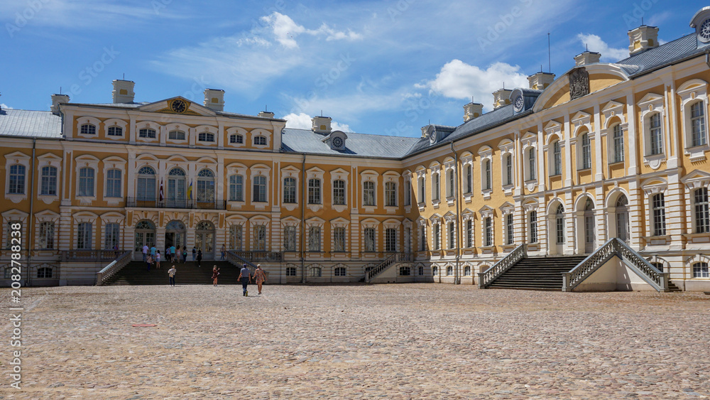 Obraz premium Rundale Palace with Baroque architecture featuring ornate columns, sculptural gate and wide cobblestone courtyard. Historic residence, European heritage, tourism destination and classical design