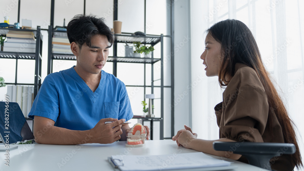 Fototapeta premium Dentist Examining Healthy Tooth Model While Consulting Patient